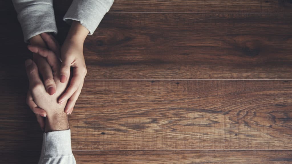 hand holding hand across wooden table