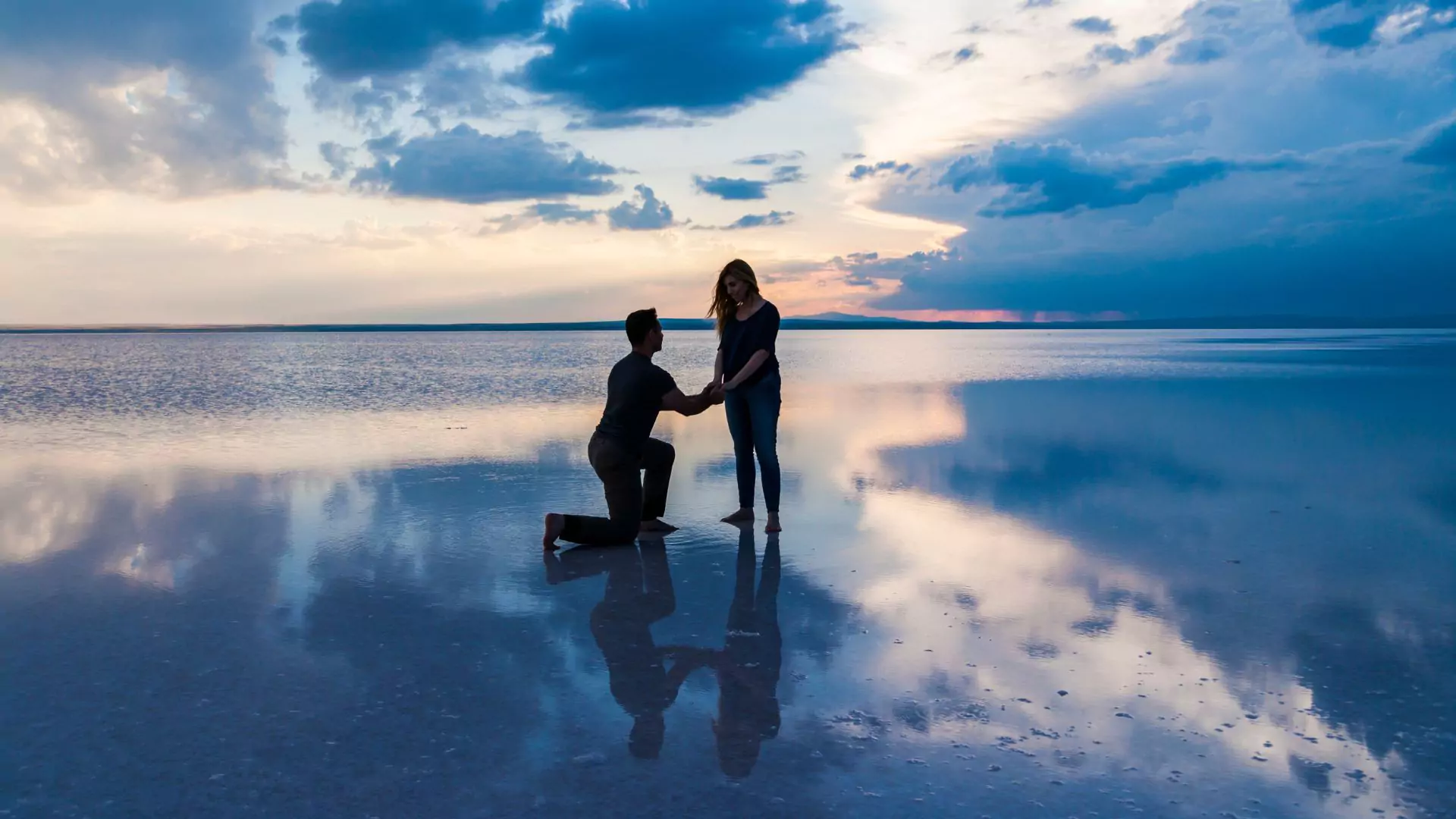 photo of man proposing to girlfriend on the beach at sunset. Get ready to wed by combatting common marriage scams.