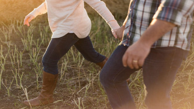 man and woman holding hand wearing denim pants on grass field