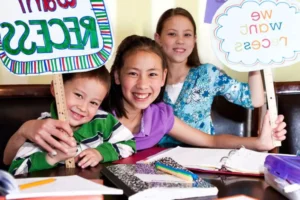 three kids of all different ages sitting at the table with their shoolbooks