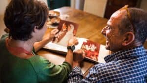 Photo of a couple going through a photo album and remembering how they each love their spouse.