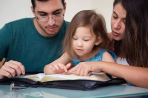 mom, dad and daughter studying the bible together