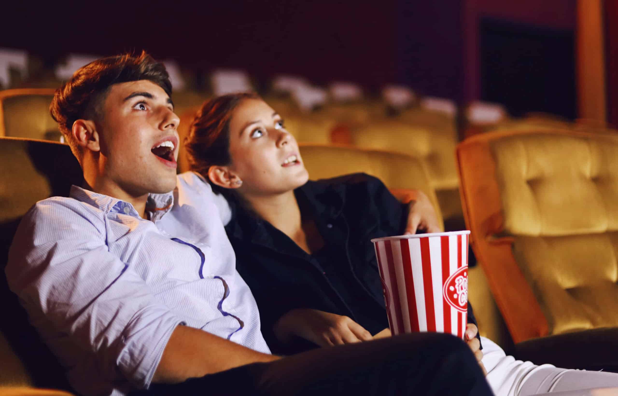 a young man and woman watch a movie in the theater