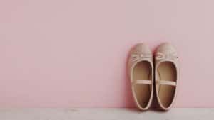 Little girl's pink ballet slippers against pink background