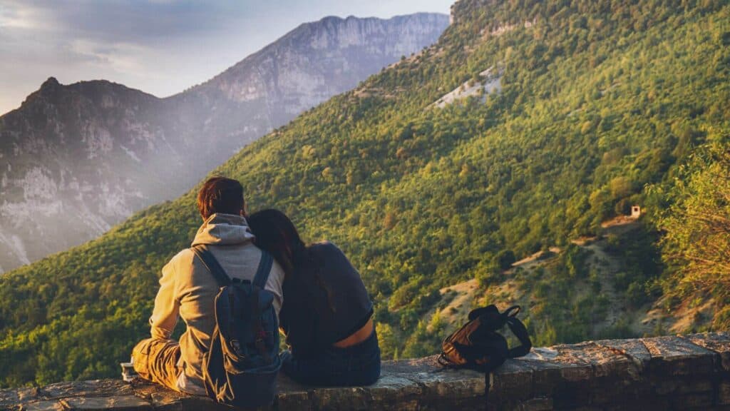photo-couple-on-their-annual-marriage-getaway-resting-on-their-hike-looking-at-mountains