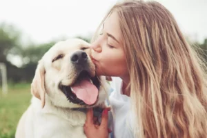 Young girl kissing her dog on the nose