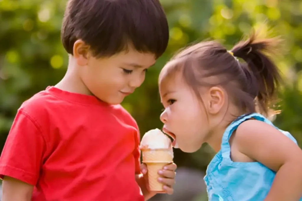 Young boy sharing his ice cream with a young girl