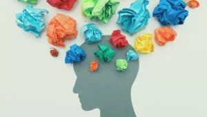 A silhouette of a face profile with dozens of crumpled pieces of colored paper above it, signifying a person's difficulty in identifying their emotions with soul words.
