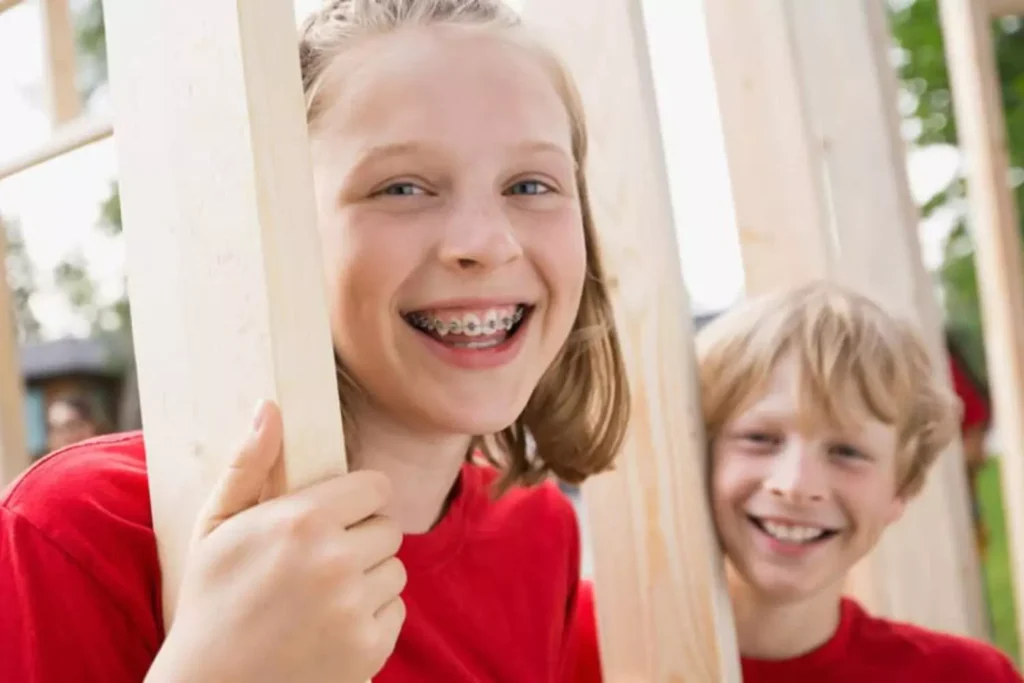 Tween siblings in red shirts smiling in a construction site