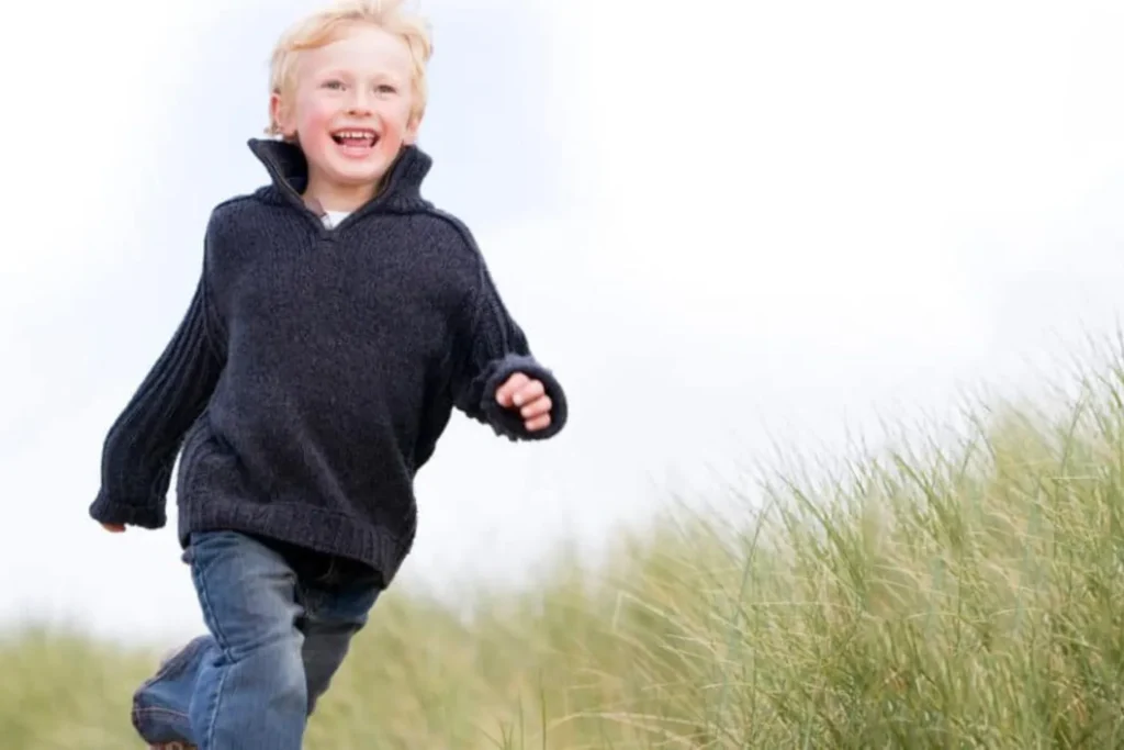 School-age boy smiling and running through grass