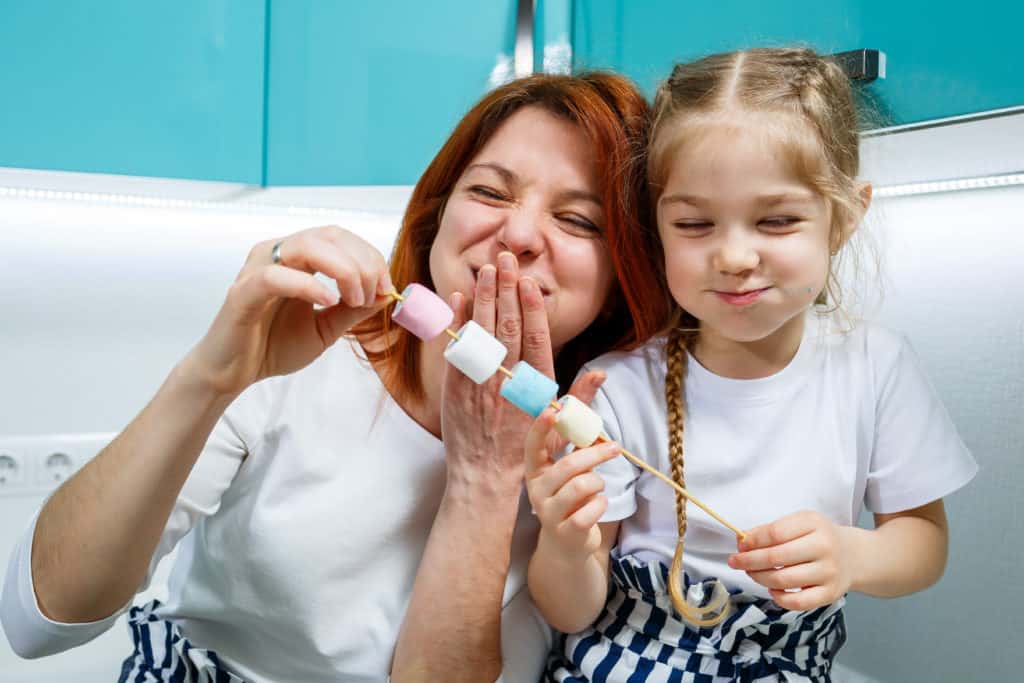 Mom and daughter, each eating a marshamallow