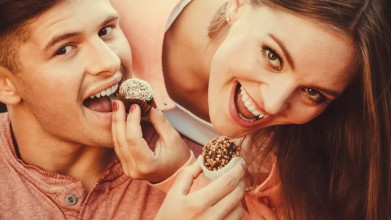 A man and woman invest in friendship in their marriage by playfully feeding each other sweets.