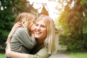 Smiling mom holding her young daughter outdoors, illustrating the joy of baby bunching.