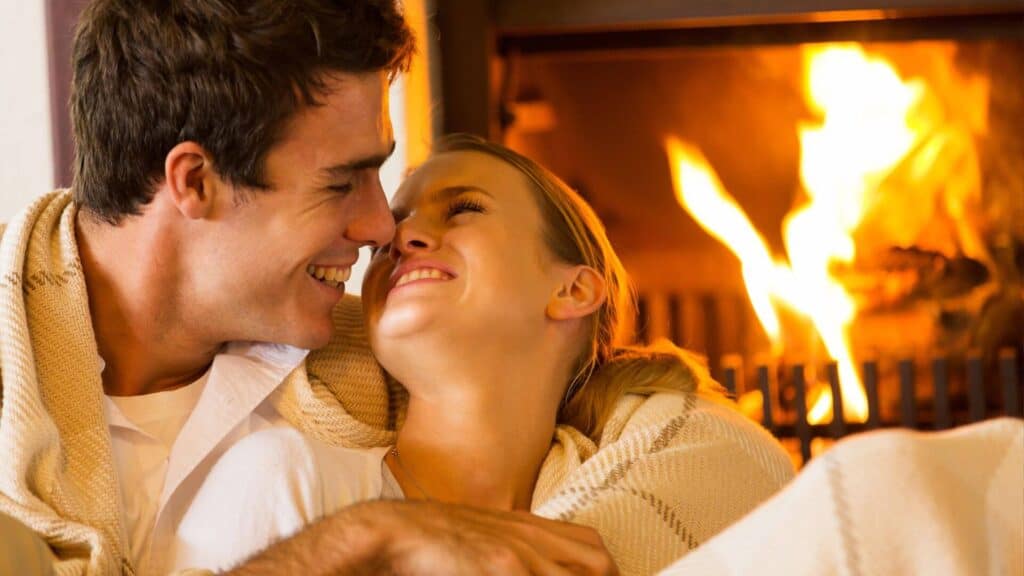 Photo of married couple cuddling by the fire. God's amazing design for sex gives them joy and freedom in their sex lives.