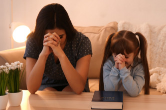 Mom praying with young daughter