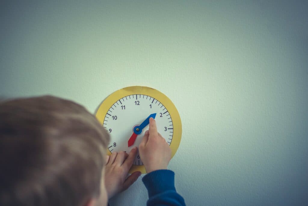young child changing the time on a manual clock