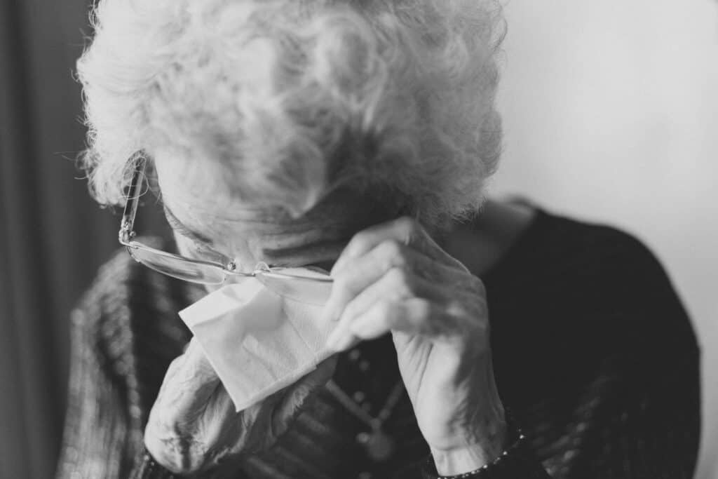black and white pic of elderly woman wiping away tears