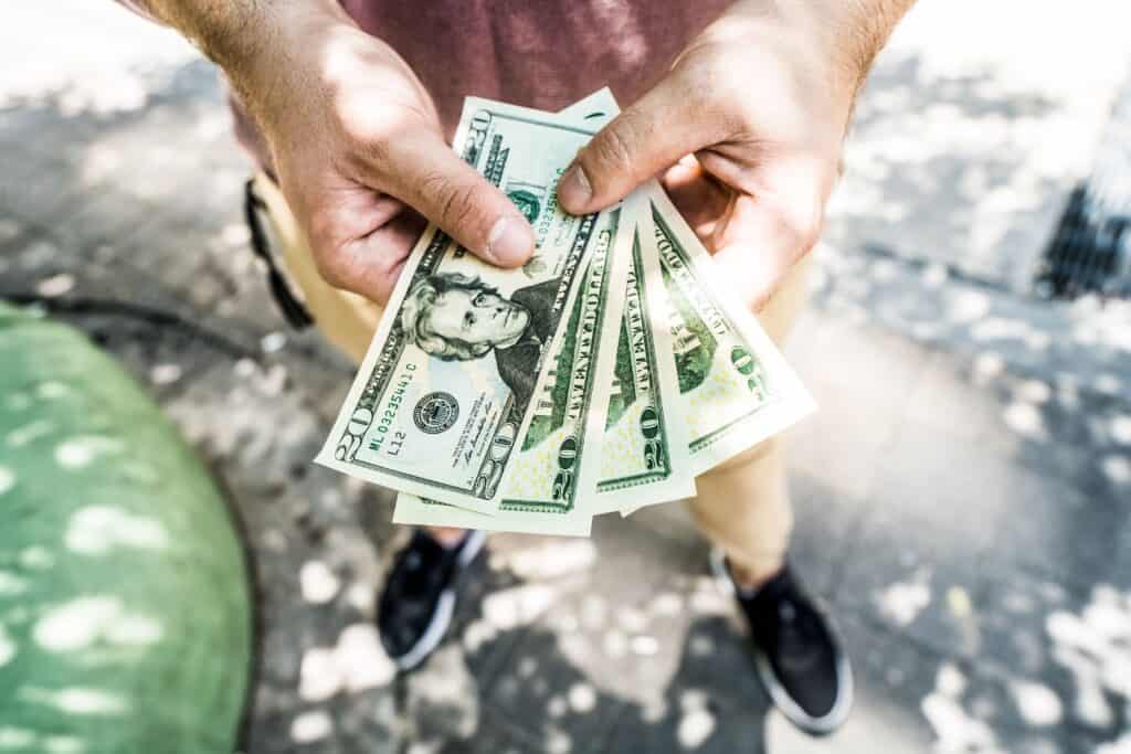 man holding handful of 20 dollar bills