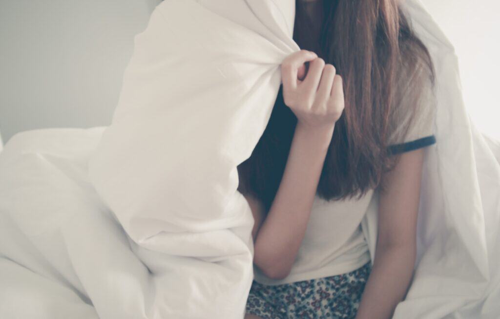 teen girl hiding under bedspread