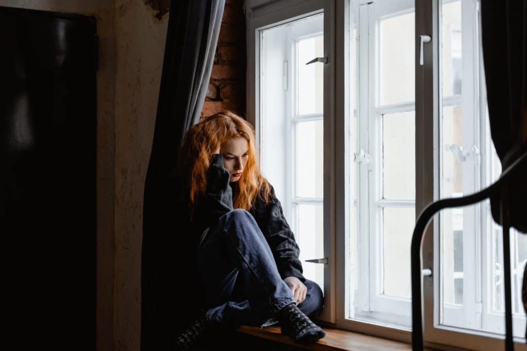 sad teen girl sitting by window