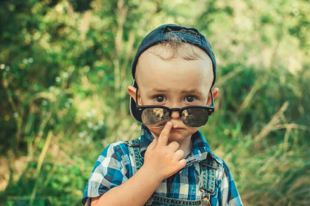 sad little boy wearing grown up sunglasses