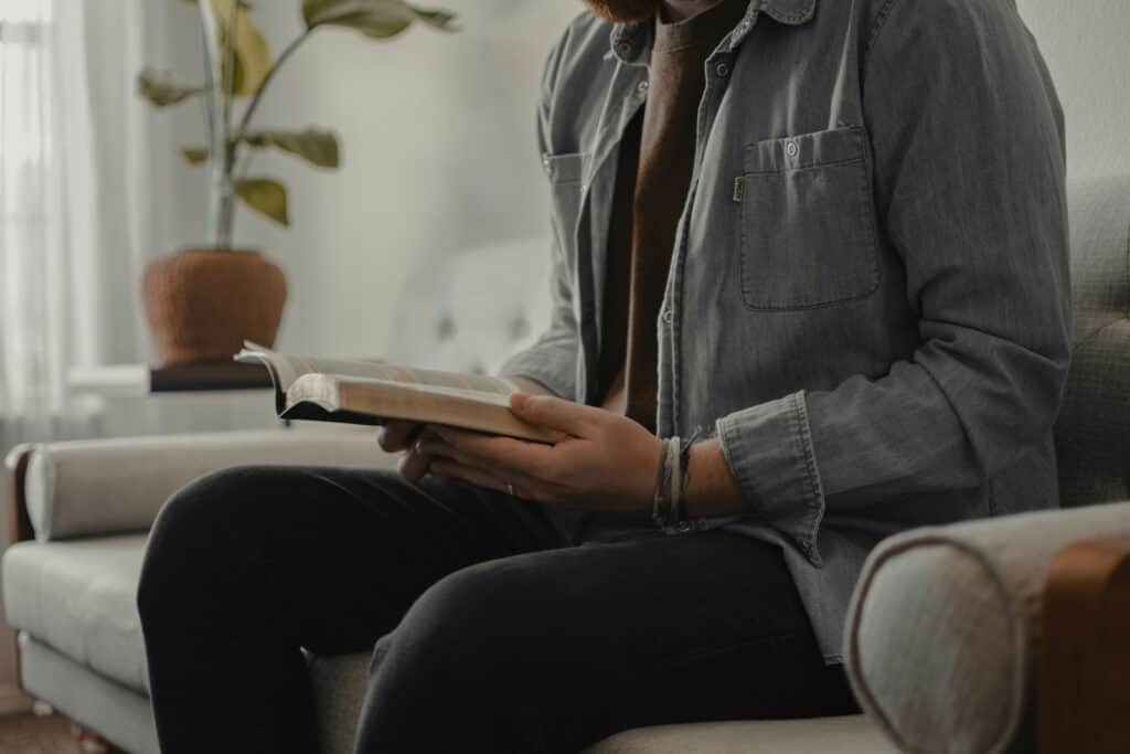 man on couch reading Bible