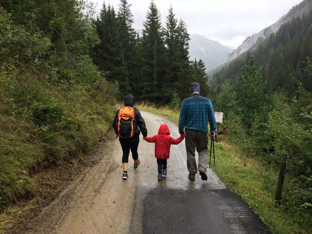 mom dad and child hiking near pines and mountains