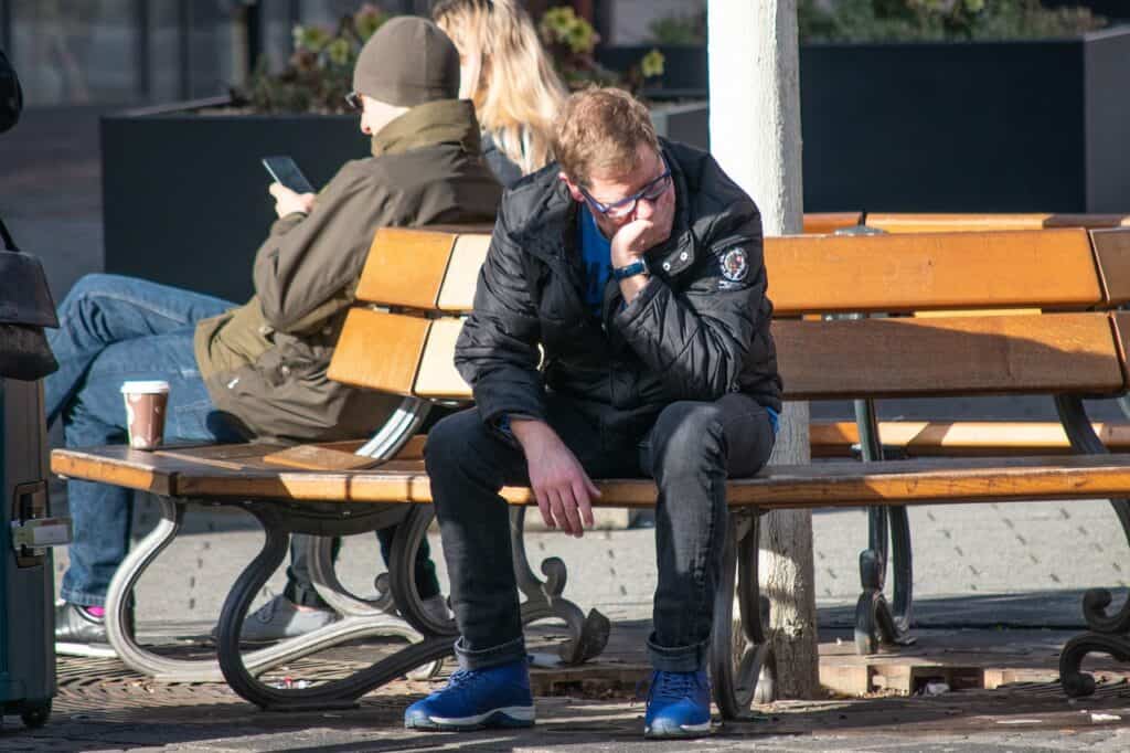 Man looking dejected head in hand on bench