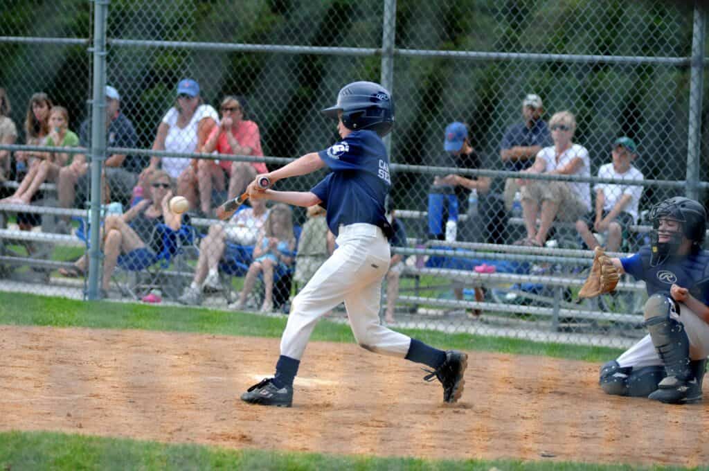 kid hitting baseball in little league game
