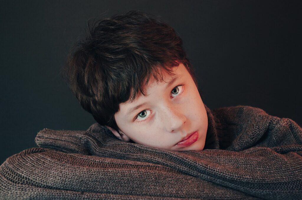 boy looking sad lying on blanket