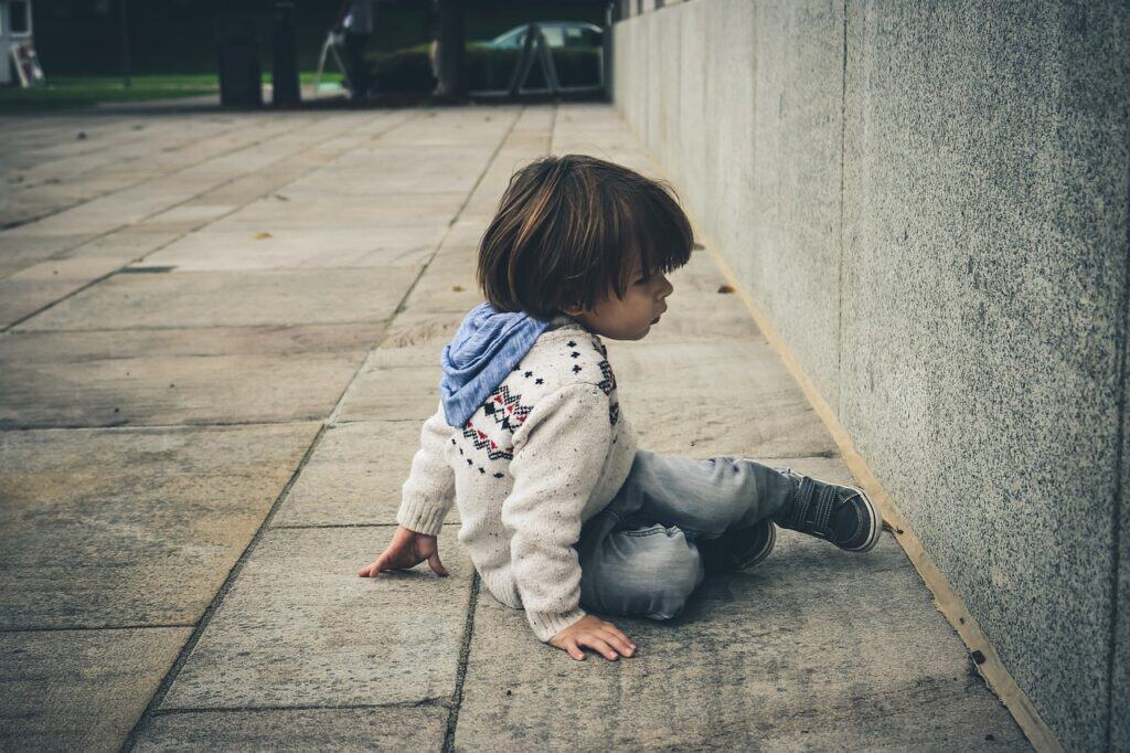 boy sitting on ground by wall