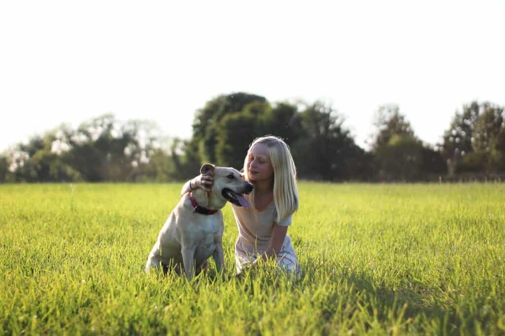 girl and dog in field of grass