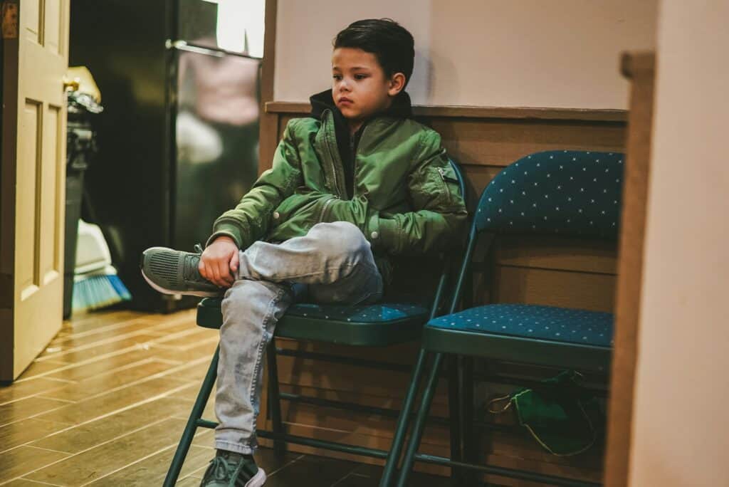 boy sitting on chair in hallway