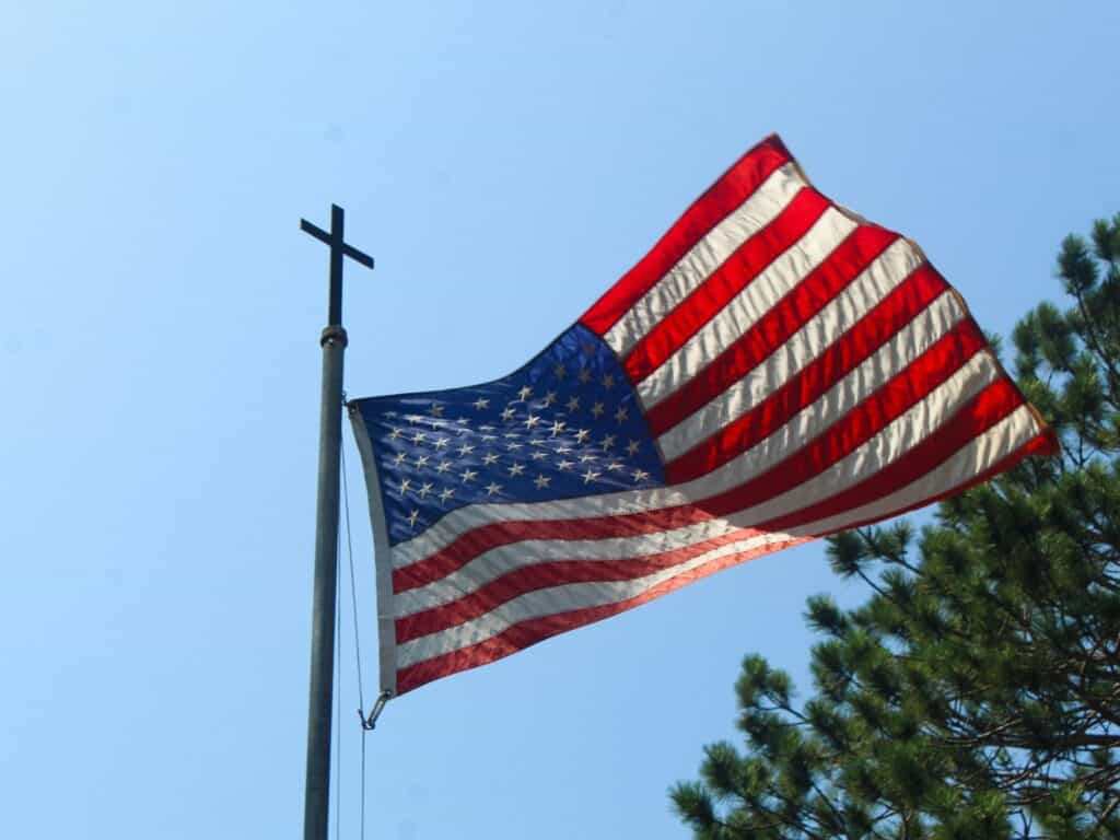 American flag on flagpole topped with cross