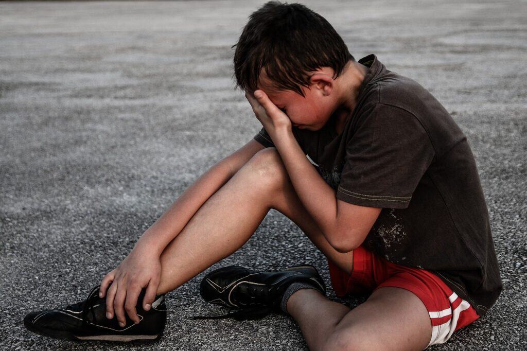 Boy sitting on ground upset