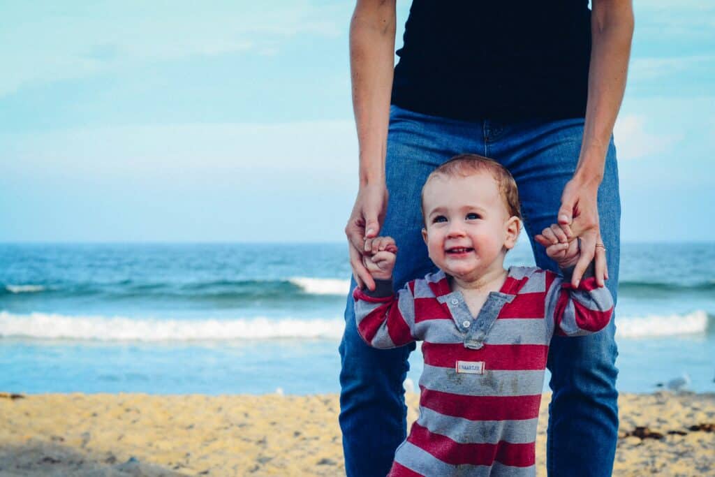 person walking on beach with baby
