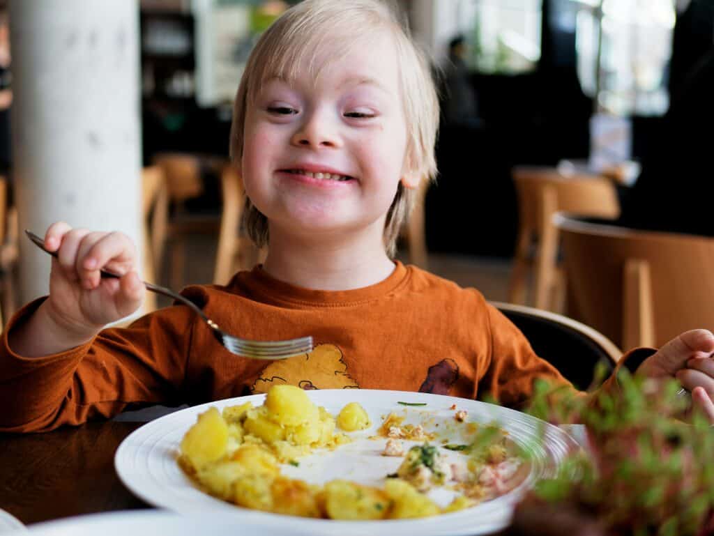 boy with downs eating and grinning