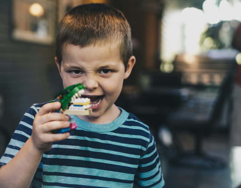 boy with angry face holding toy dinosaur