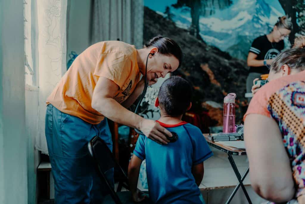 doctor in scrubs with stethoscope checking small boy
