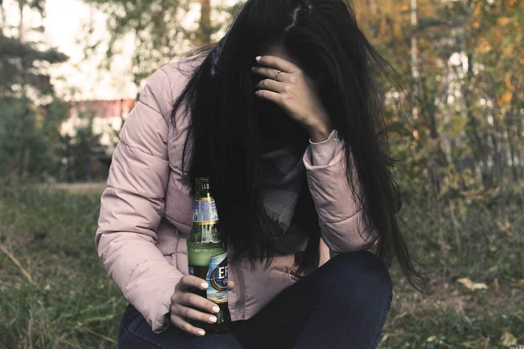 woman with bowed head drinking beer