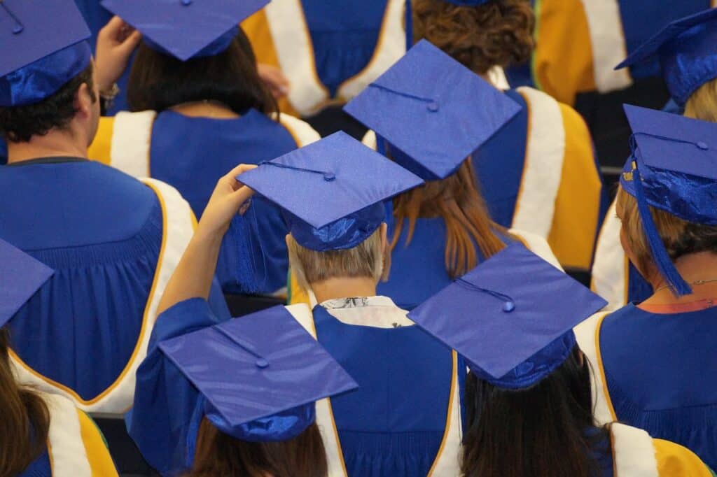 backs of students in caps and gowns