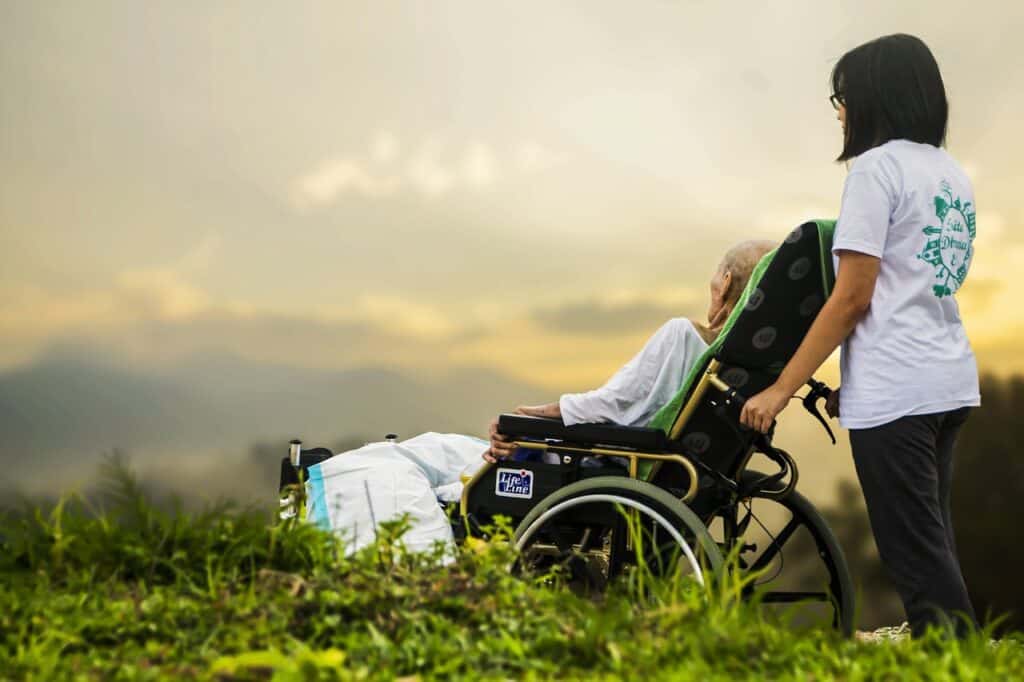 Woman pushing elderly woman wheelchair sunset
