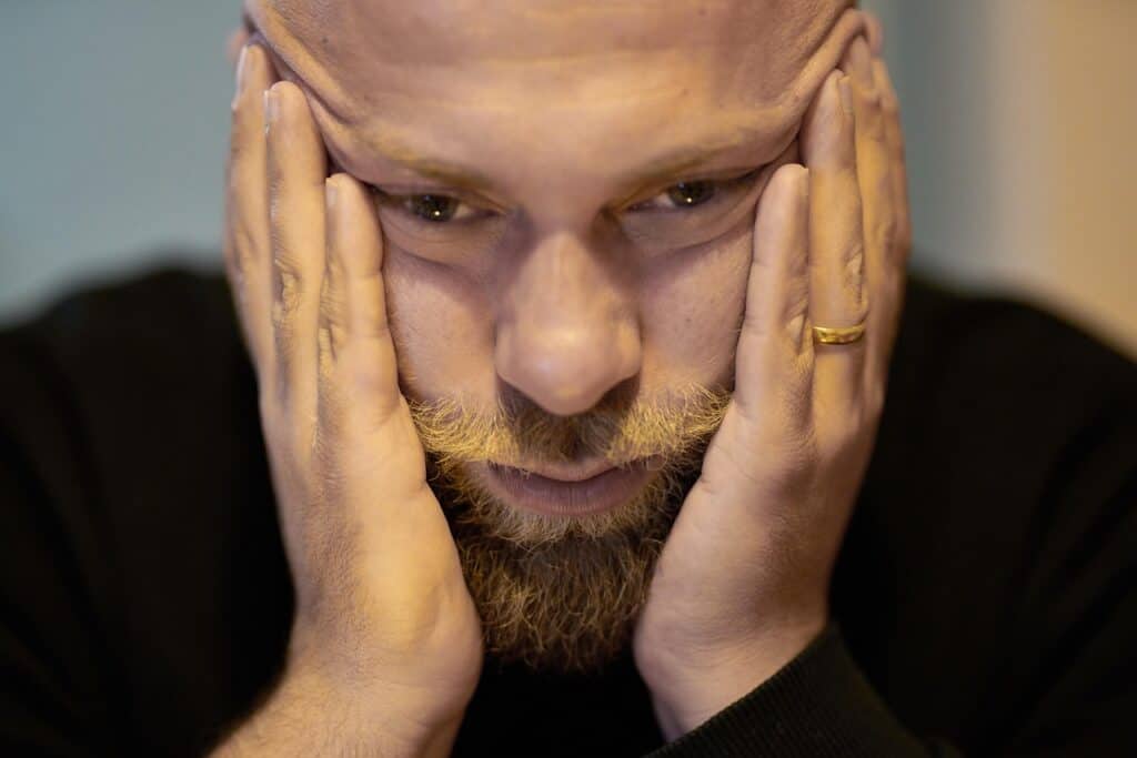 married man hands holding face looking unhappy