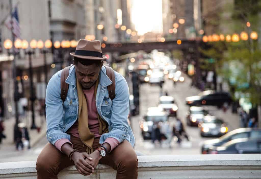 sorrowful man sitting on wall overlooking city