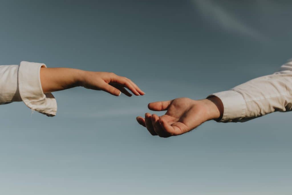 man and woman hands reaching toward each other to help