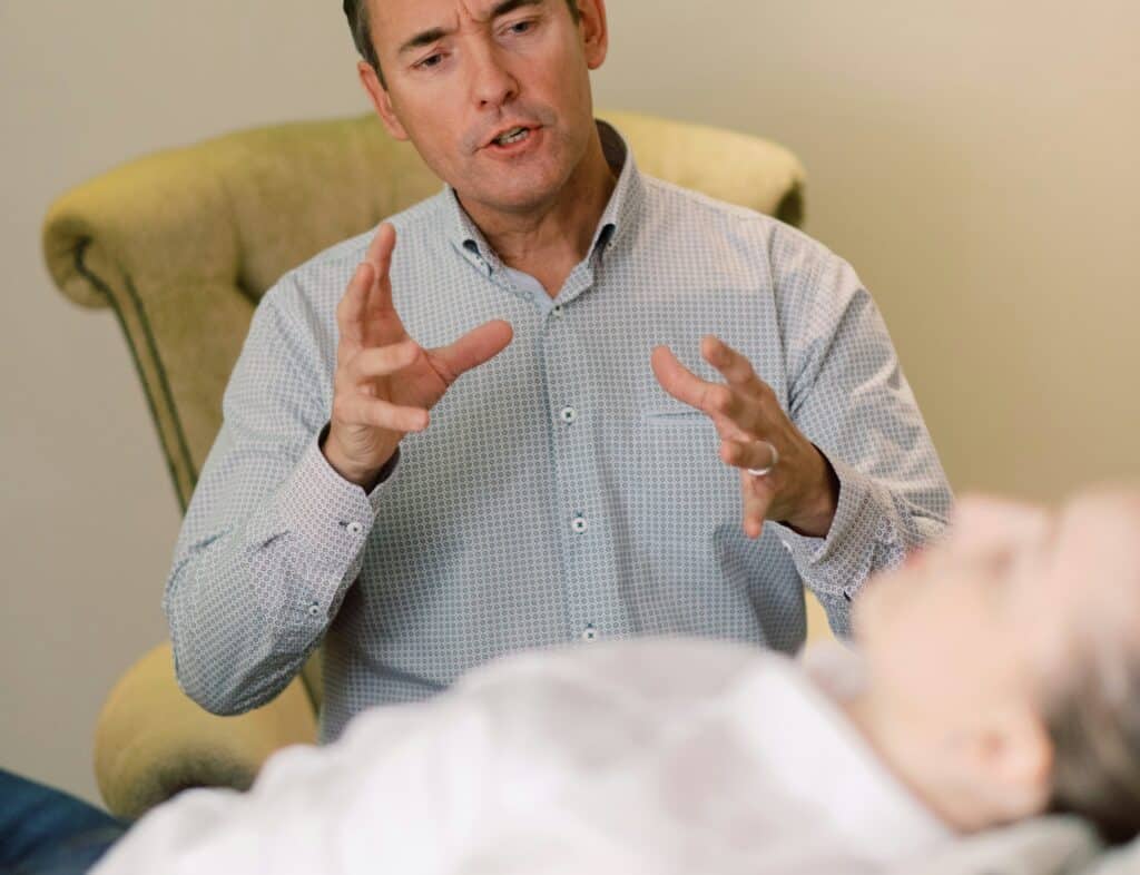 man therapist talking describing to female patient lying down