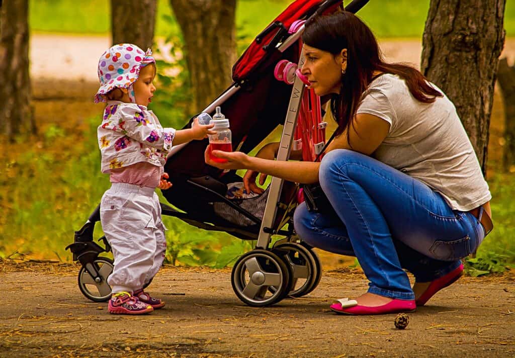 woman with stroller crouched down with toddler