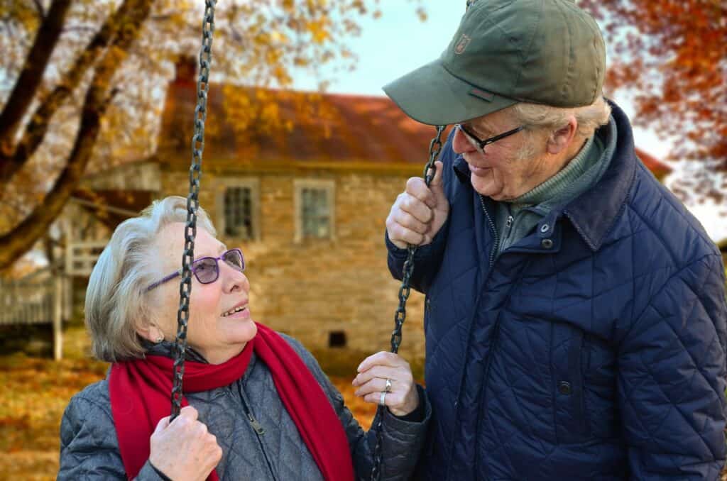 senior lady on swing with senior man next to her