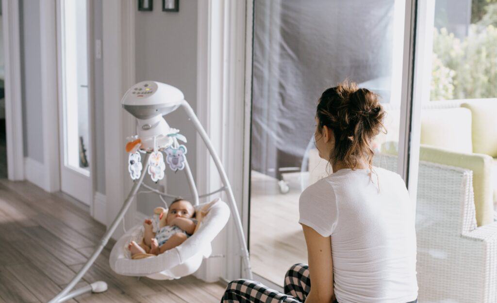 mother watches baby in swing
