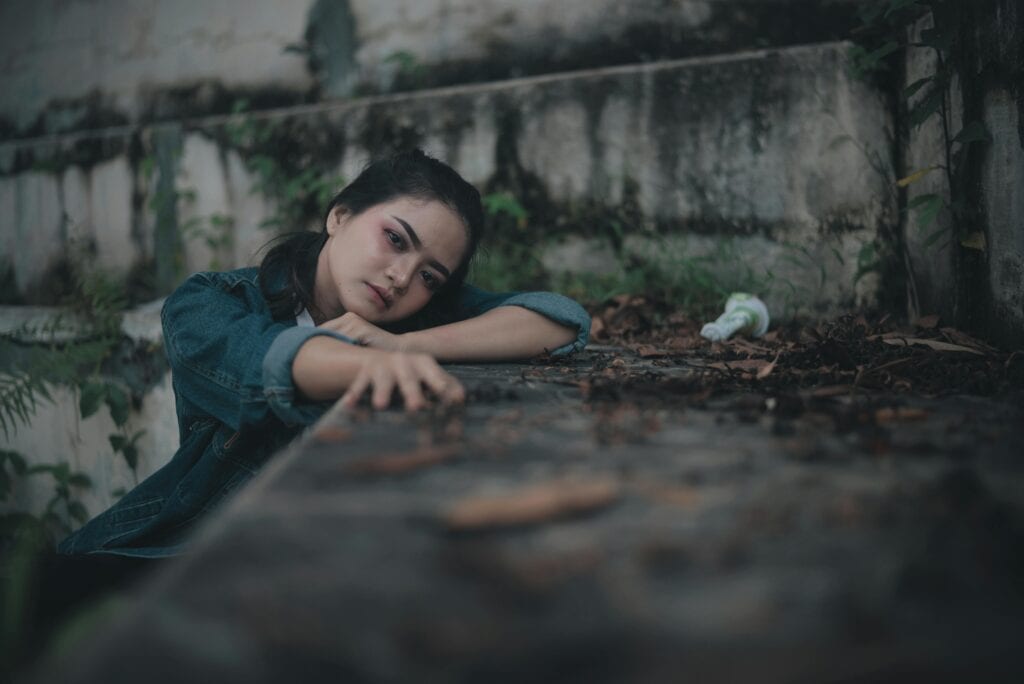 girl lying against stone building stretching out arm depressed